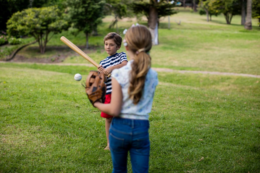 boy and girl playing baseball with a wiffle ball